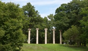 Columns on a hill surrounded by green trees 