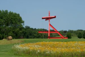 red sculpture in field of flowers