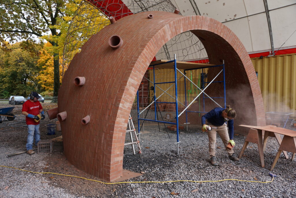 team of masons working on half completed Puryear commission: an archway of brick with wire support in the shape of a dome ascending from the archway