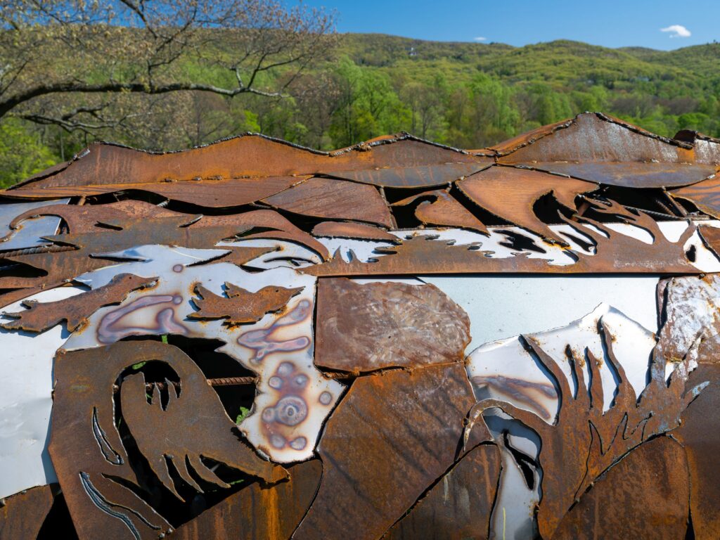 A close up of thin metal cut out in animal shapes with lush green trees in the background.