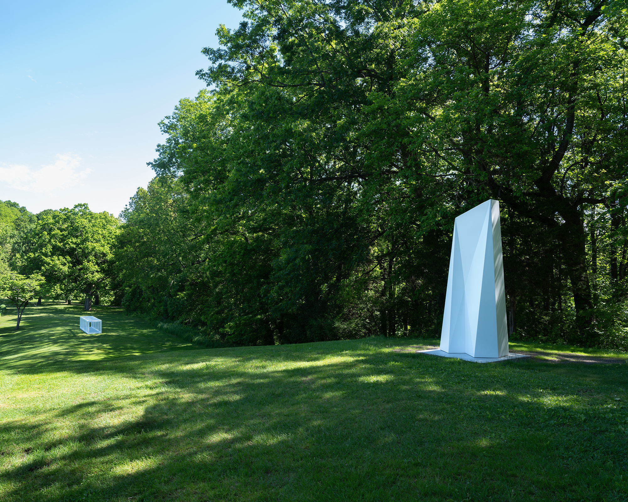 A white polygon totem sits in on top a grassy hill.